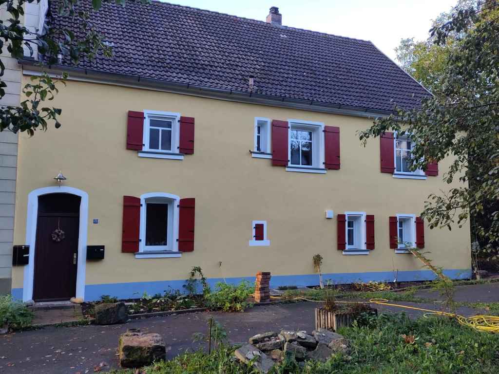 GELBES HAUS MIT ROTEN FENSTERLAEDEN